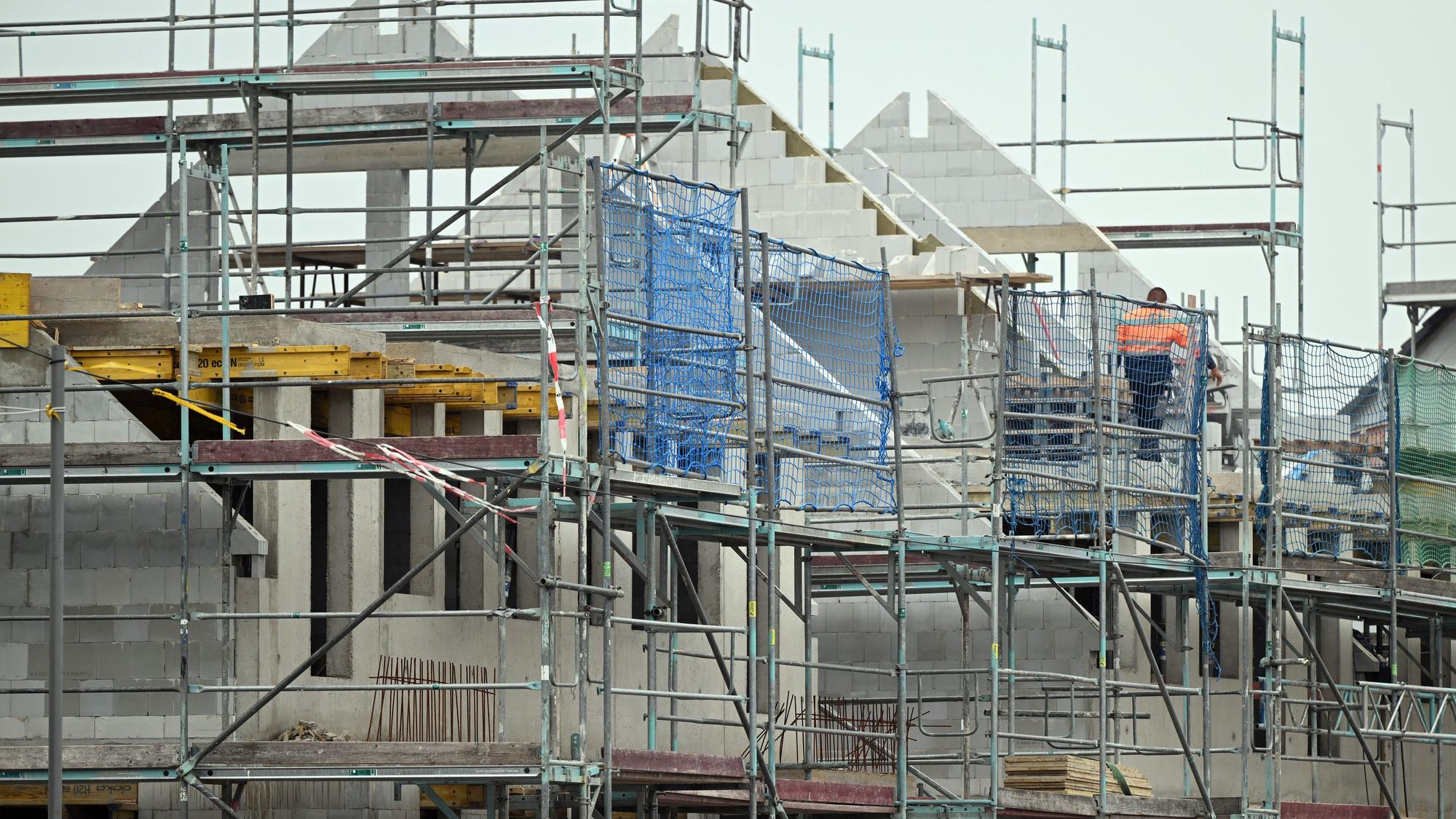 Gerüste stehen an noch nicht fertig gebauten Häusern in einem Neubaugebiet.
