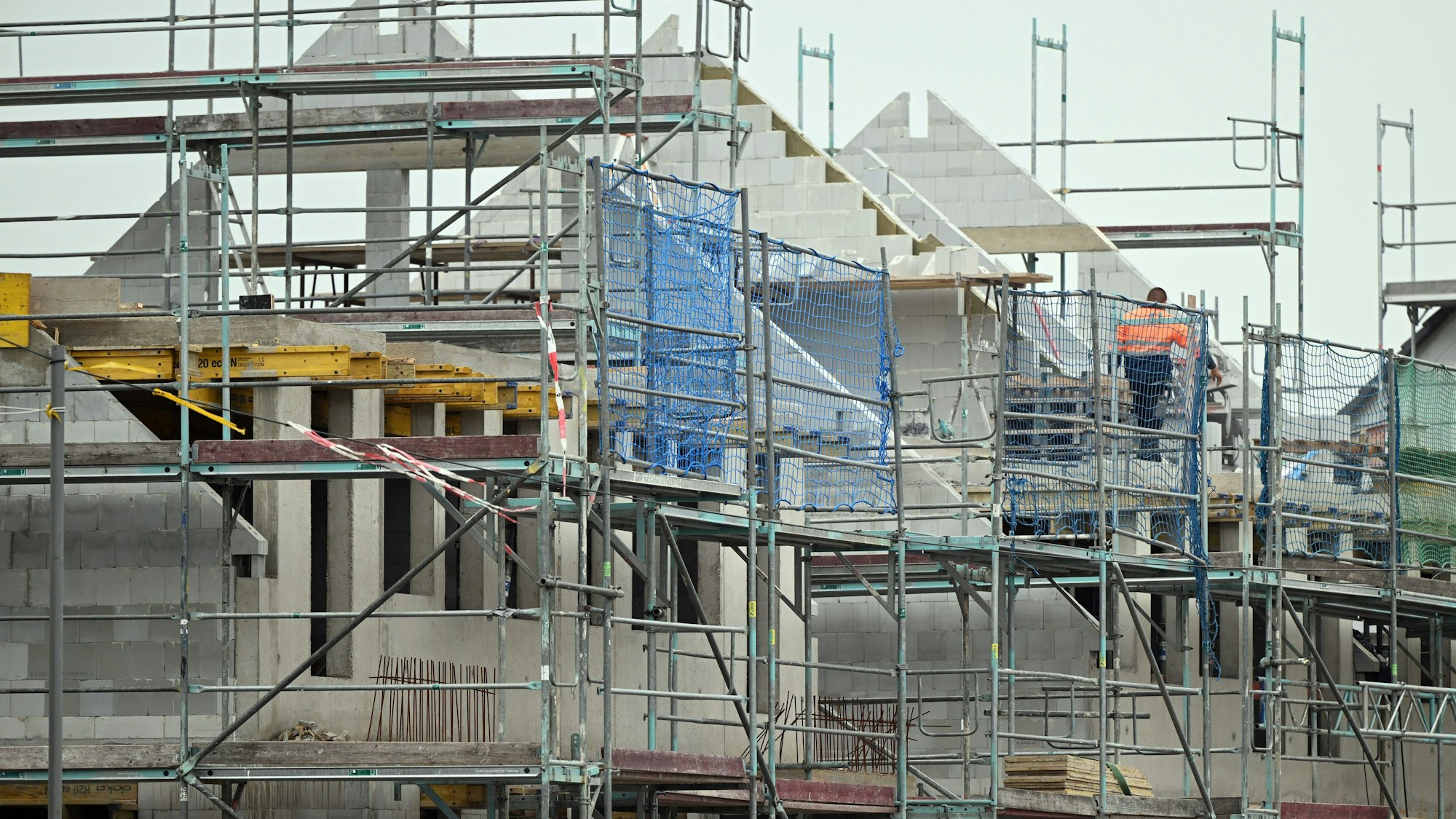 Gerüste stehen an noch nicht fertig gebauten Häusern in einem Neubaugebiet.