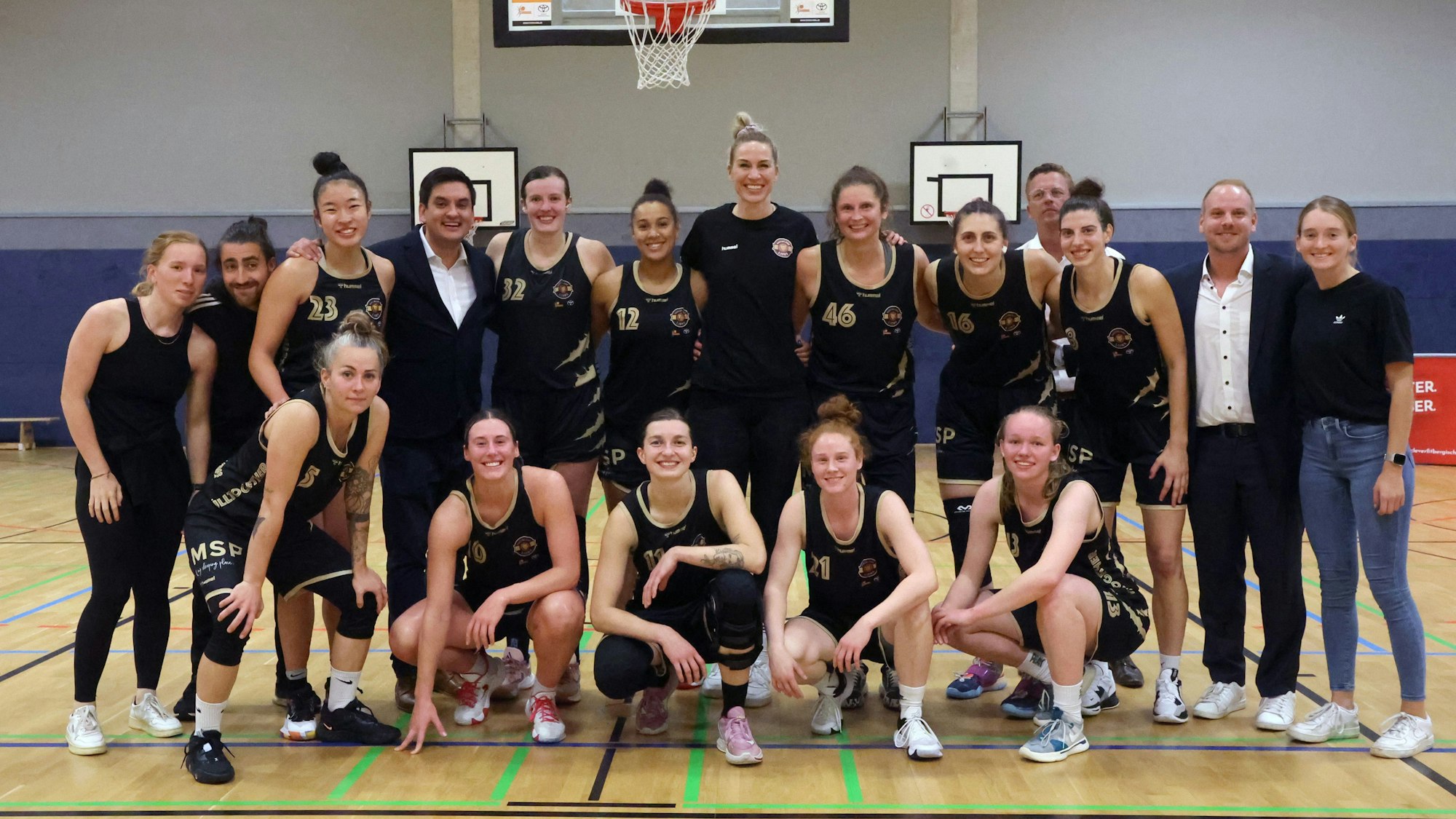 Die Basketballerinnen der Rheinland Lions in ihren schwarzen Trikots in einer Turnhalle.