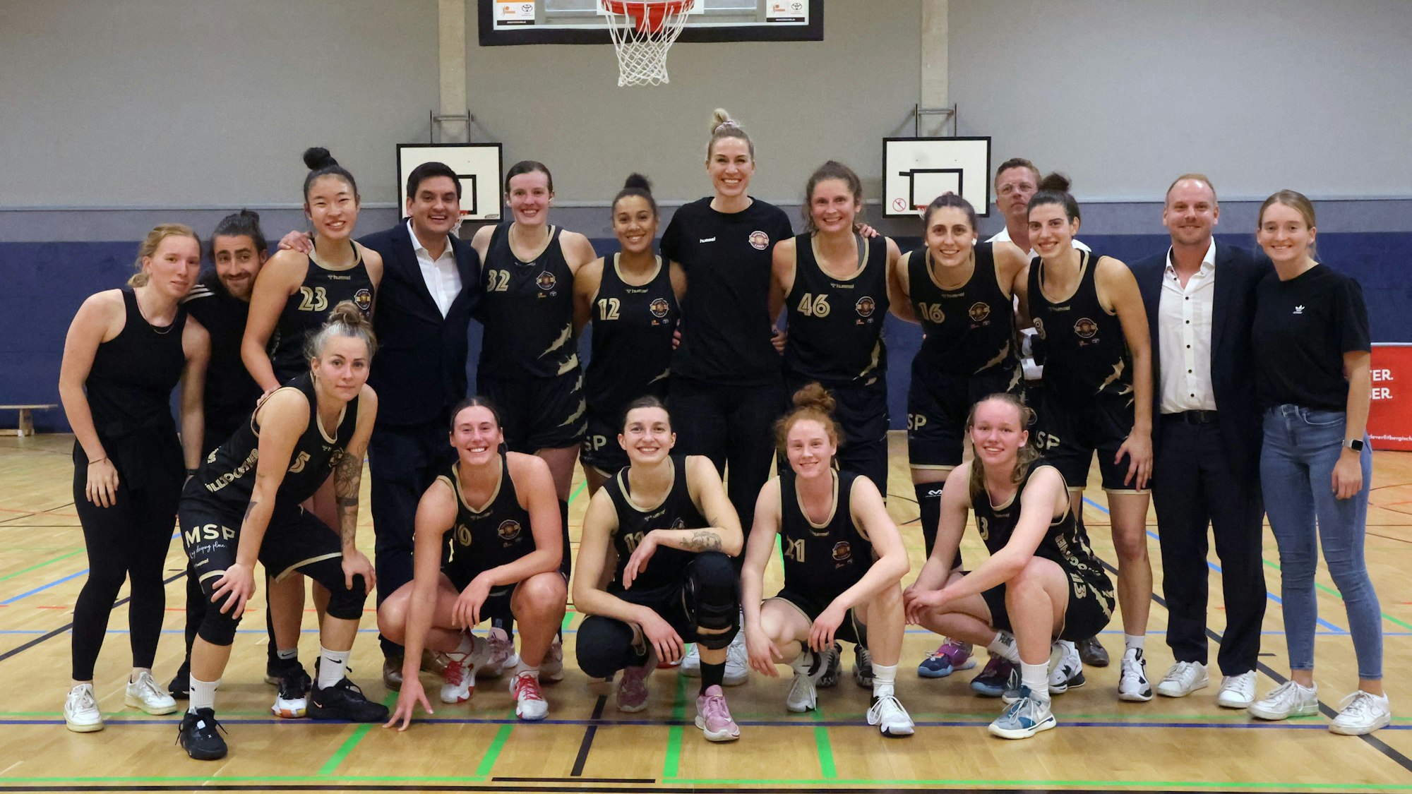 Die Basketballerinnen der Rheinland Lions in ihren schwarzen Trikots in einer Turnhalle.