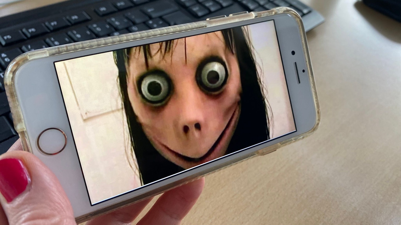 Ein Bild der Gruselfigur Momo ist auf einem Handy zu sehen.