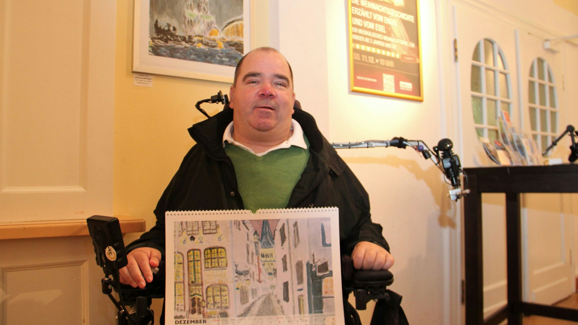 Ein Mann im Rollstuhl hat ein Bild mit einer Straßenansicht auf dem Schoß.