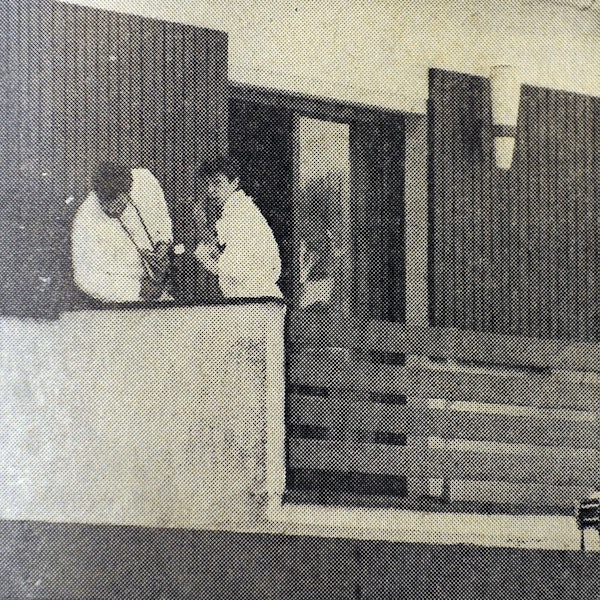 Zwei Beamte in weißen Anzügen suchen auf einer Veranda Spuren