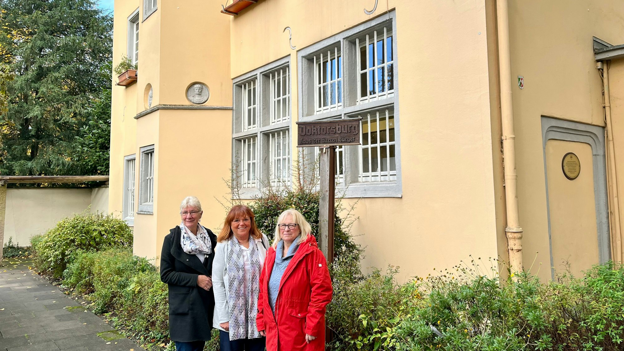 Silvia Witt, Sabine Willich, der Leiterin des Fachbereichs Soziales im Rathaus, und Petra Küppers stehen vor der Doktorsburg.