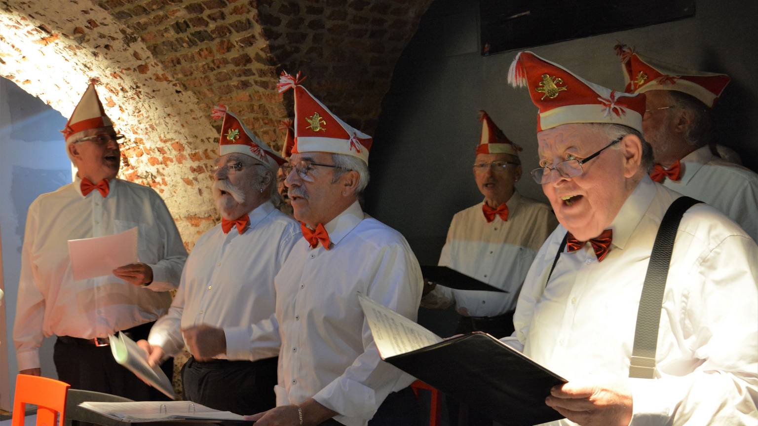 Der Chor der Roten Funken, bekleidet im weißen Hemd und rot-weißen Mützen, singt das erste Karnevalslied Kölns in der Ulrepforte.