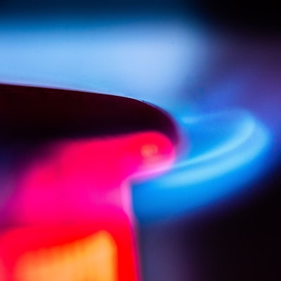 Die Flamme eines Gasherdes brennt in einer Küche.