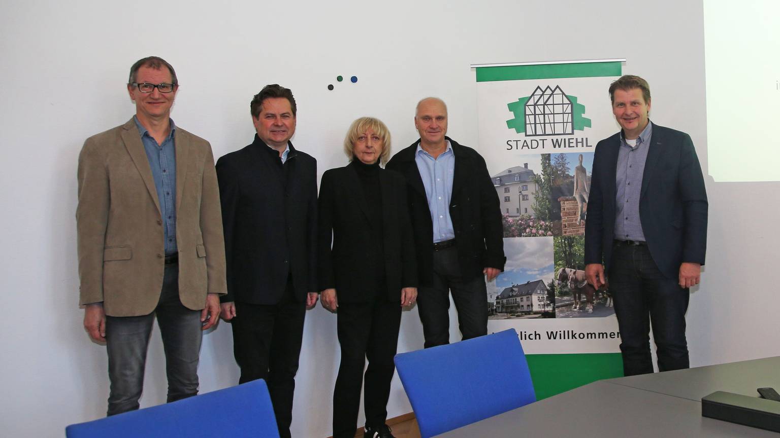 Vier Männer und eine Frau stehen vor einem Werbebanner der Stadt Wiehl.
