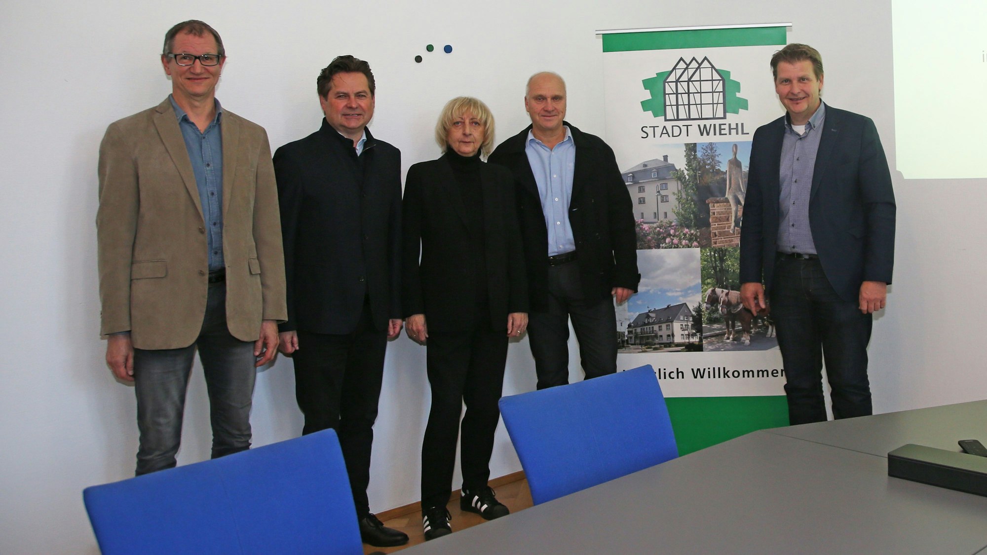 Vier Männer und eine Frau stehen vor einem Werbebanner der Stadt Wiehl.