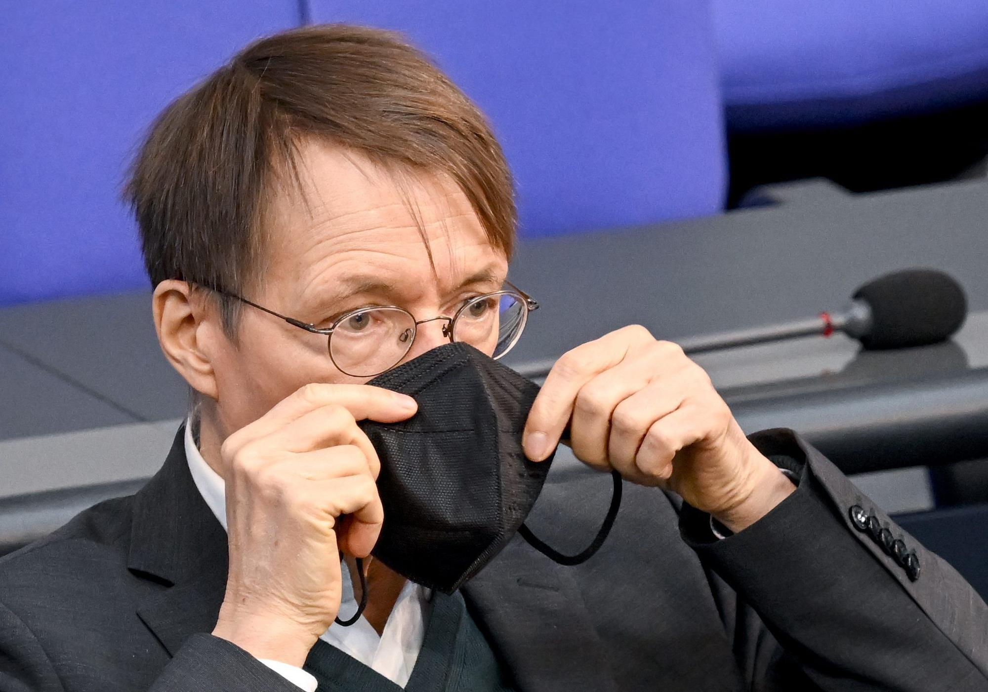 Bundesminister für Gesundheit, setzt seine Maske nach seiner Rede bei der Sitzung im Bundestag wieder auf.