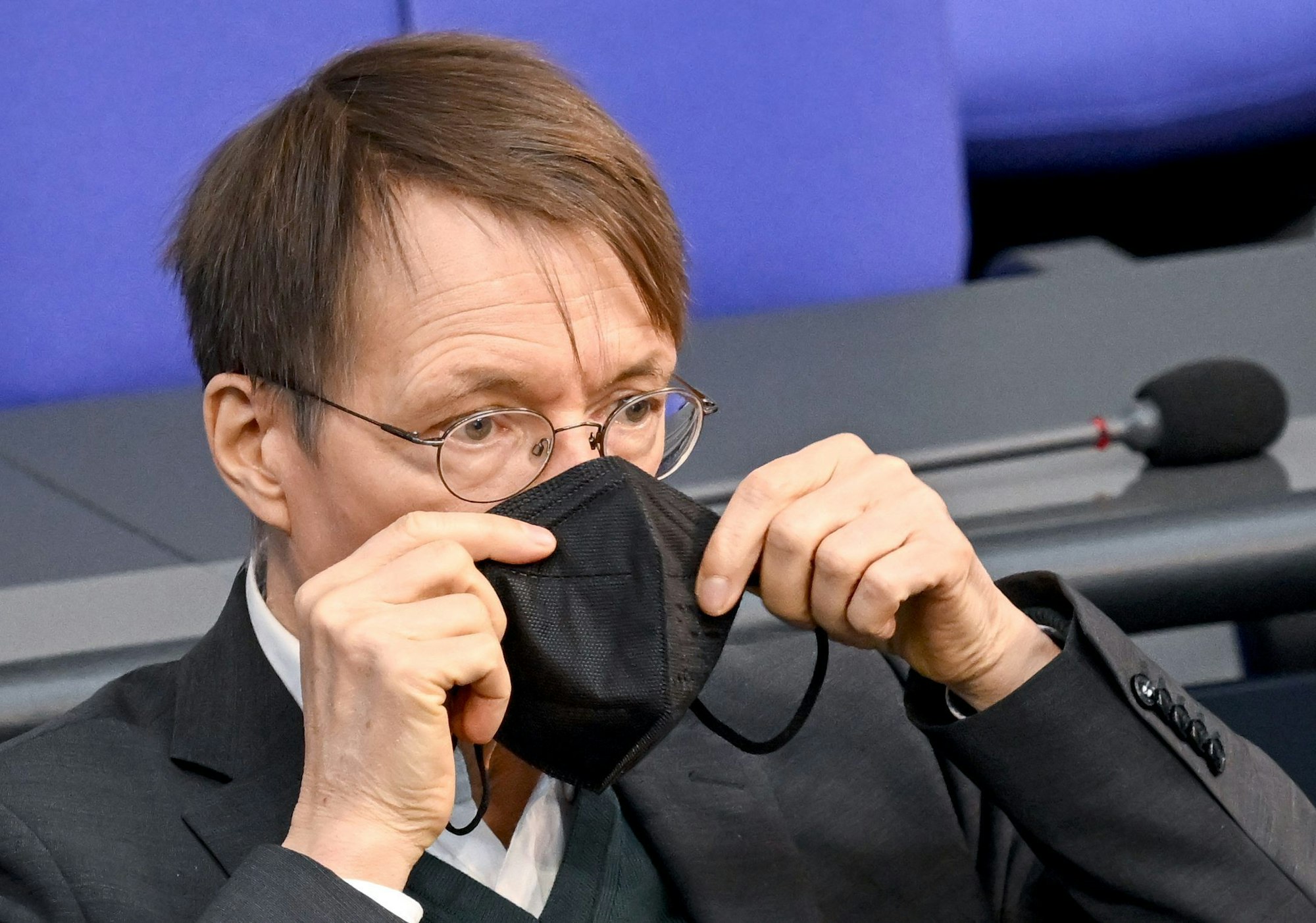 Bundesminister für Gesundheit, setzt seine Maske nach seiner Rede bei der Sitzung im Bundestag wieder auf.
