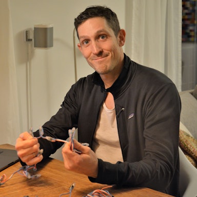 Simon Biela aus Köln-Müngersdorf in seiner Wohnung vor dem Laptop, an dem er die Lichtshow programmiert hat. In der Hand hält er eine der Lichterketten.