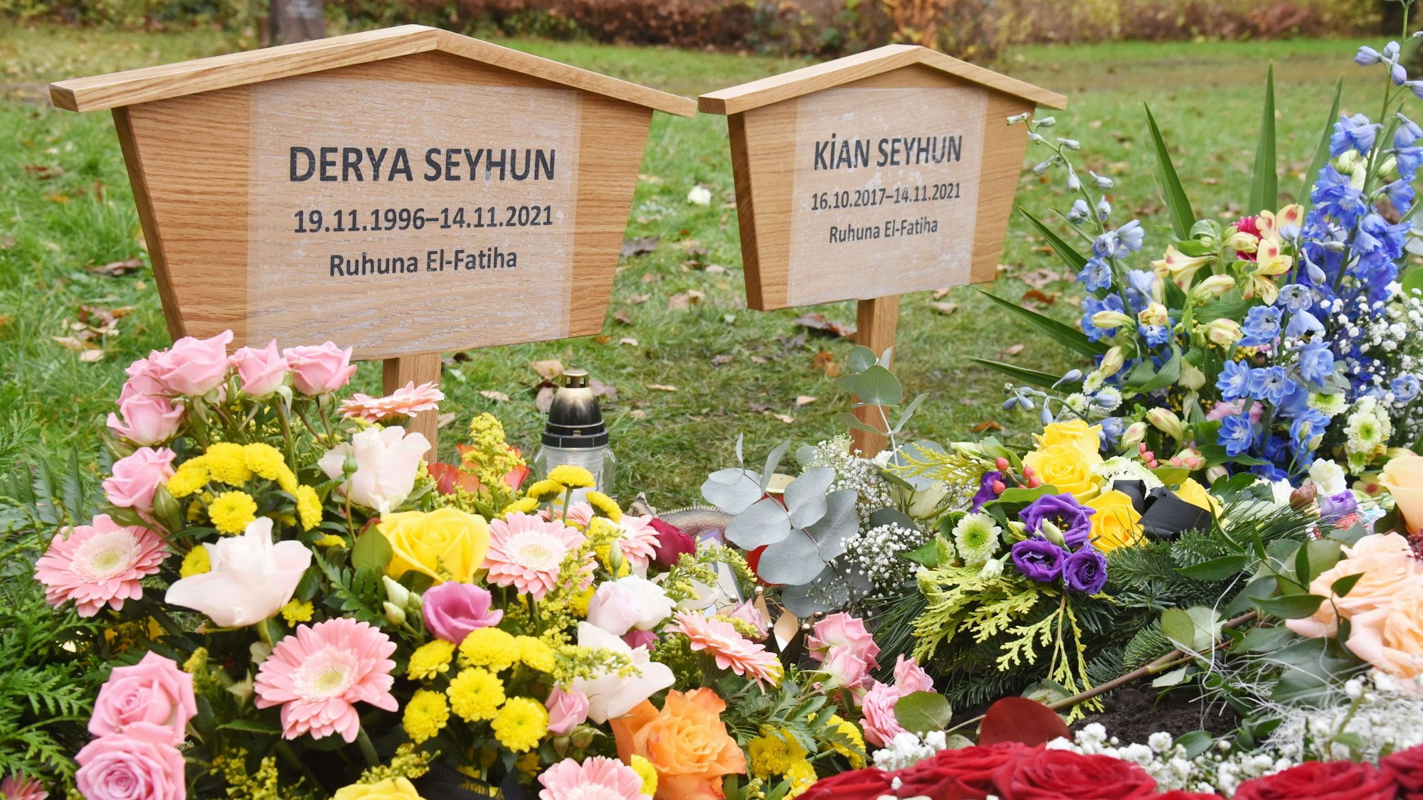 Zwei Holzkreuze stehen auf dem mit Blumen geschmückten Grab von Derya und Kian Seyhun auf dem Friedhof in Chorweiler.