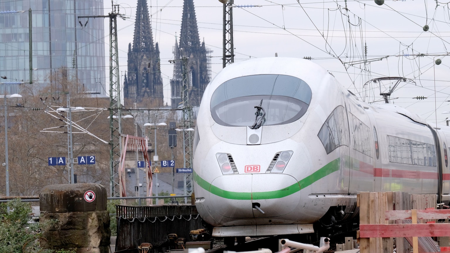 Ein ICE fährt im Bahnhof Messe/Deutz ein, im Hintergrund ist der Kölner Dom zu sehen.