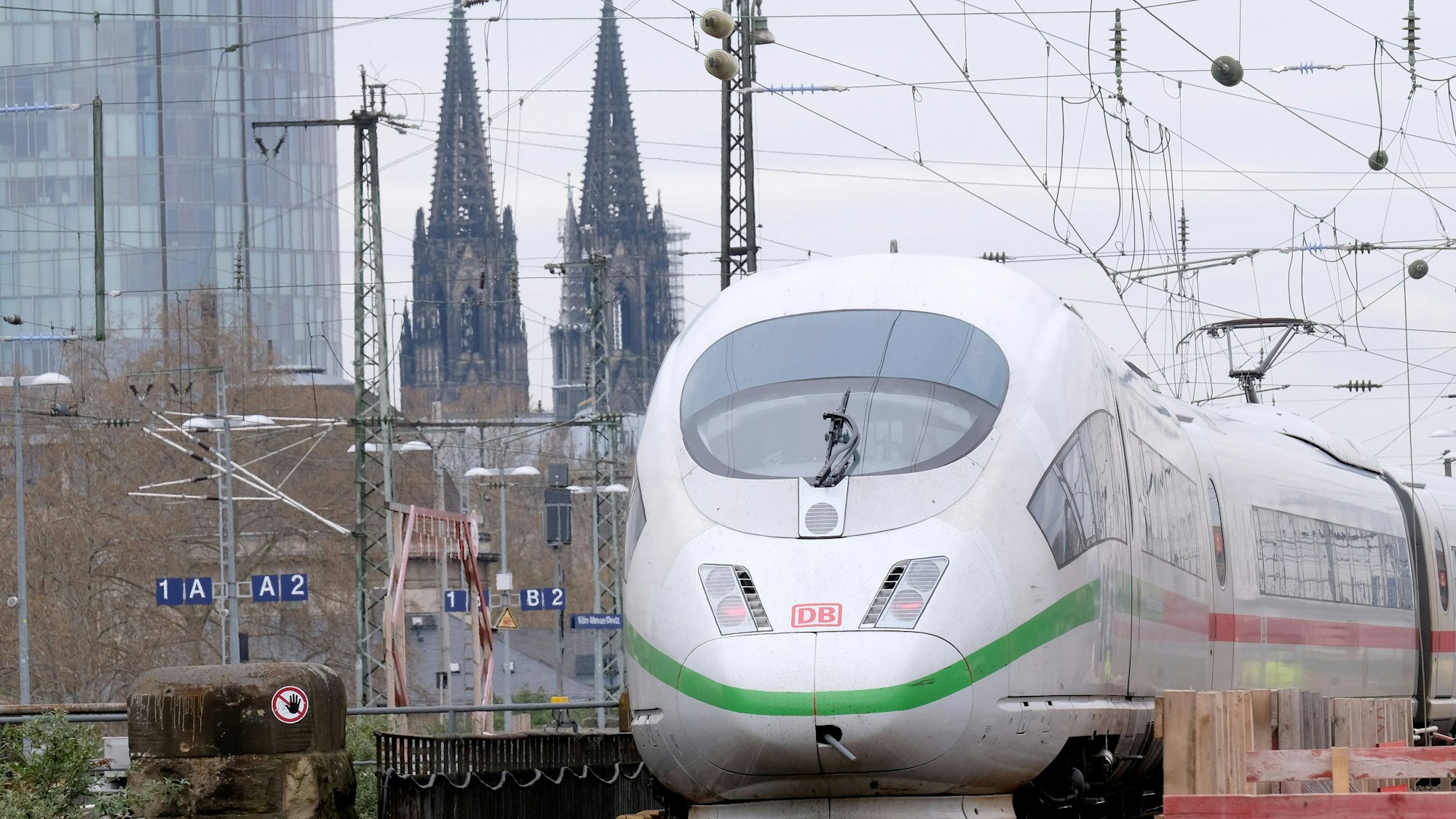 Ein ICE fährt im Bahnhof Messe/Deutz ein, im Hintergrund ist der Kölner Dom zu sehen.