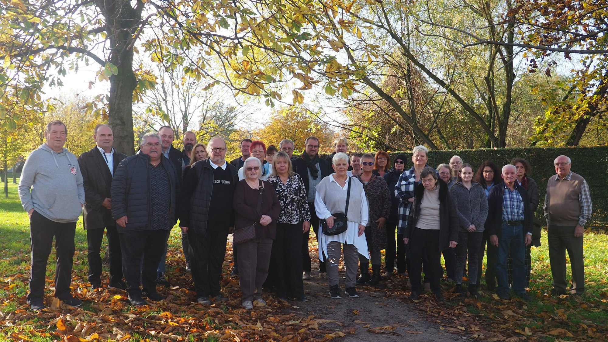 Ungefähr 30 Jubilare und Jubilarinnen stehen in einem Park.