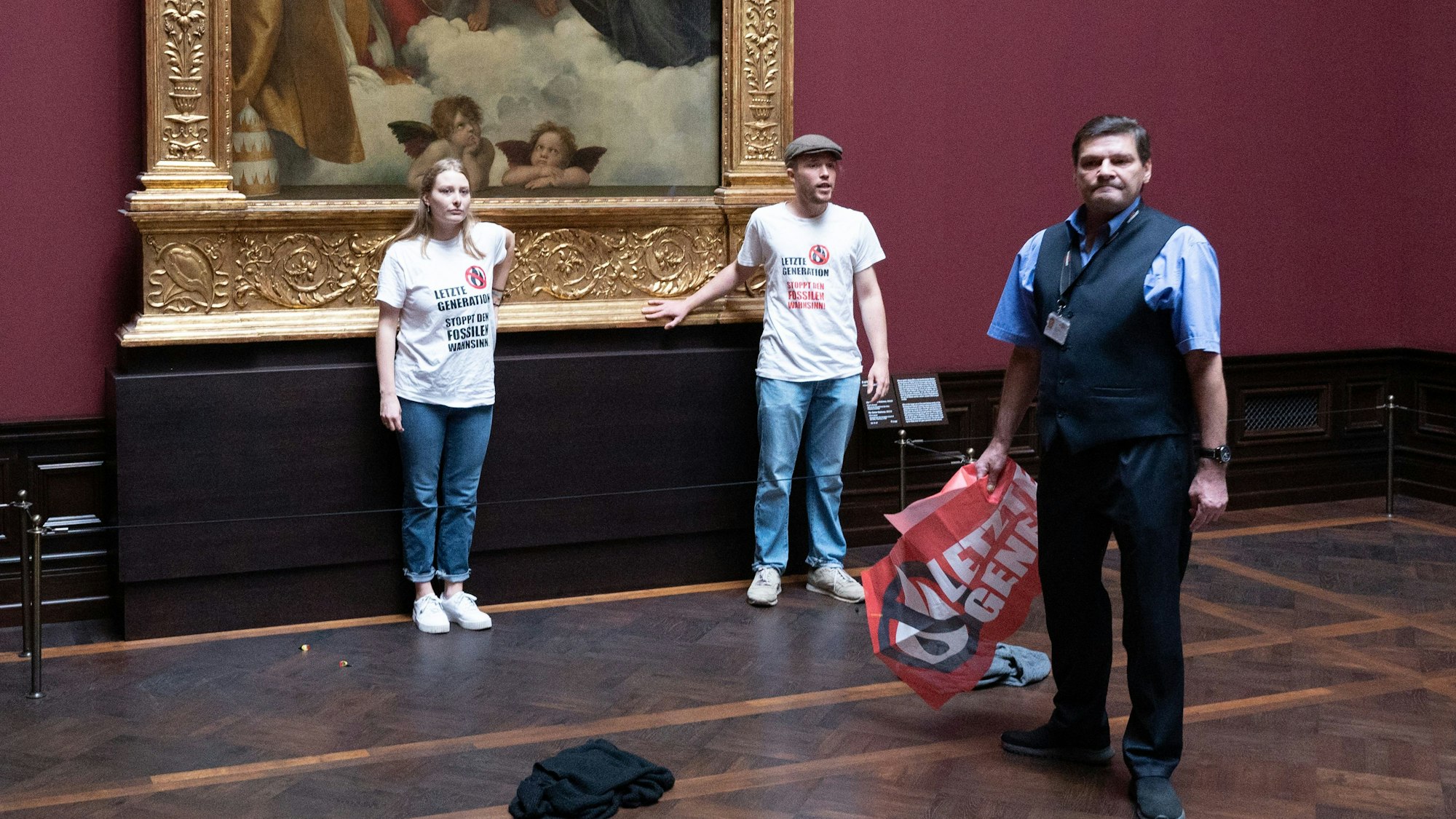 August 2022: Zwei Umweltaktivisten der Gruppe „Letzte Generation“ stehen in der Gemäldegalerie Alte Meister in Dresden an dem Gemälde „Sixtinische Madonna“ von Raffael.