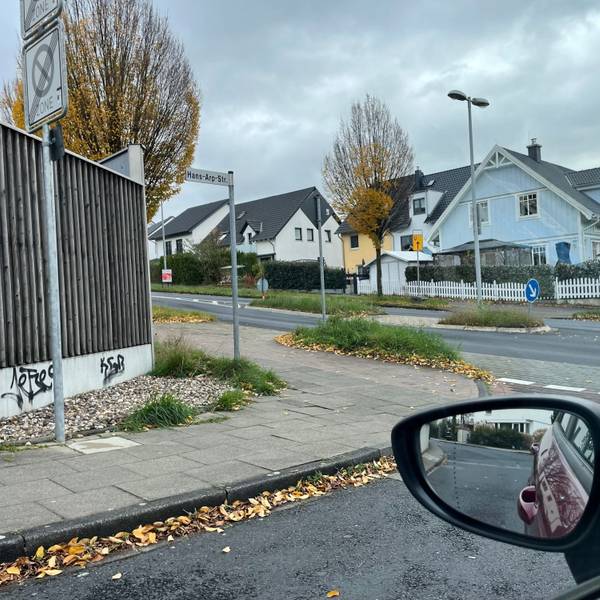 Blick aus einem Autofenster auf den Radweg, der die Hans-Arp-Straße kreuzt.