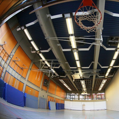 Eine leere Sporthalle im Schulzentrum Oberpleis. Oben ist ein Basketballkorb zu sehen, an einer Seitenwand lehnen blaue Sportmatten.