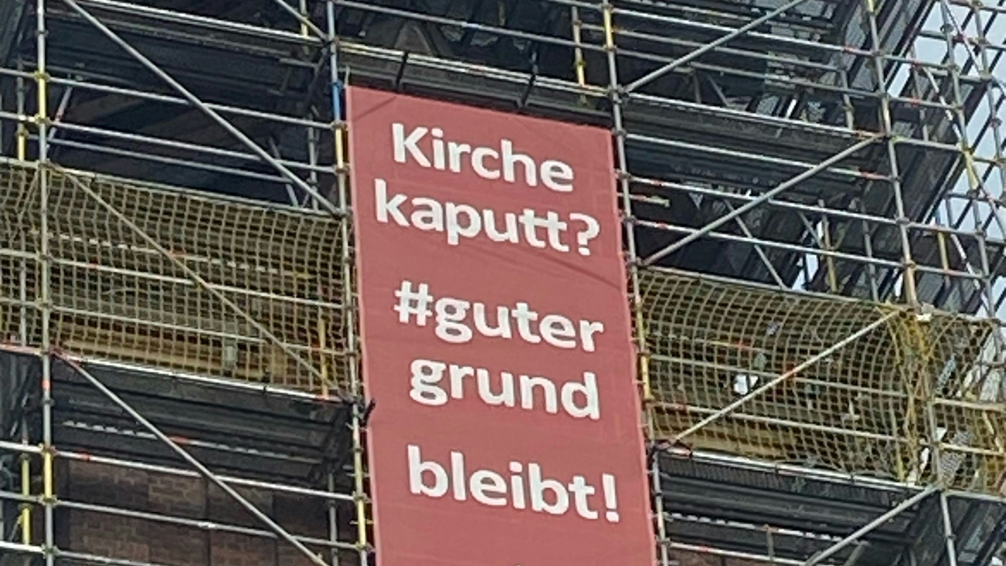 Das Banner an dem Gerüst der Kirche mit der Aufschrift „Kirche kaputt?“ – #gutergrund bleibt“.