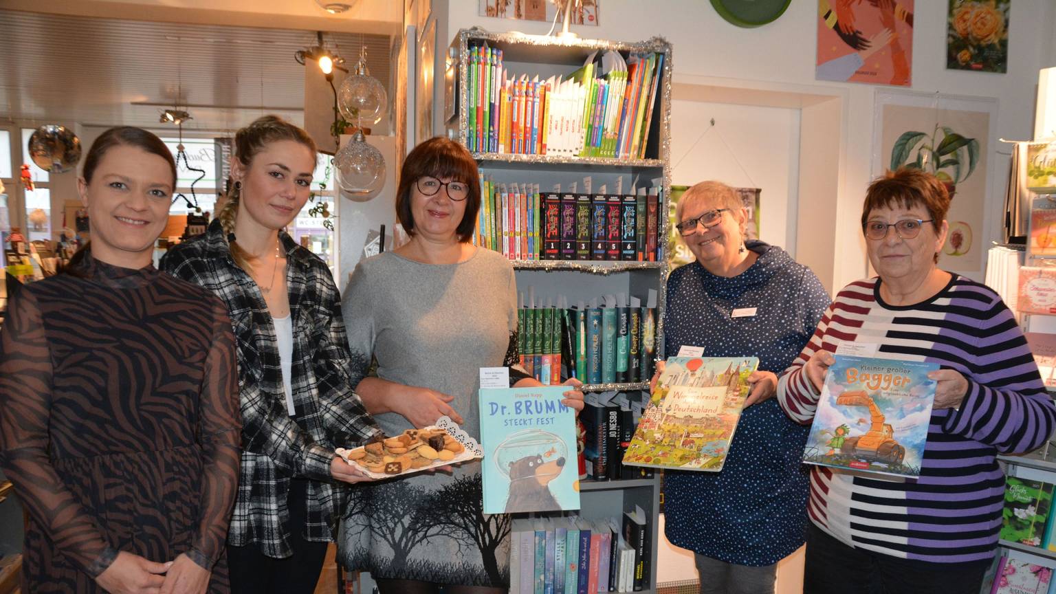 Buchhändlerin Julia Pavlik, Linda Mae Schneppenheim (Café Büchel), Ingrid Pohl (Leiterin Stadtbücherei) und Dagmar Pärsch-Roos und Angelika Legrand vom Förderverein der Bücherei stehen vor dem Aktionsregal mit Büchern.