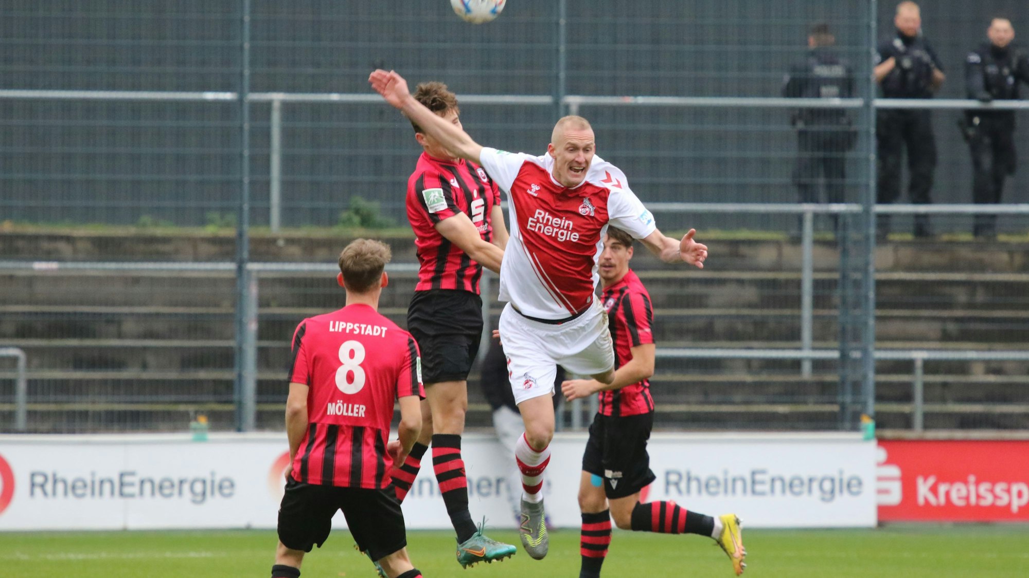 Ein Fußballer versucht, sich im Kopfball gegen drei Gegenspieler durchzusetzen.