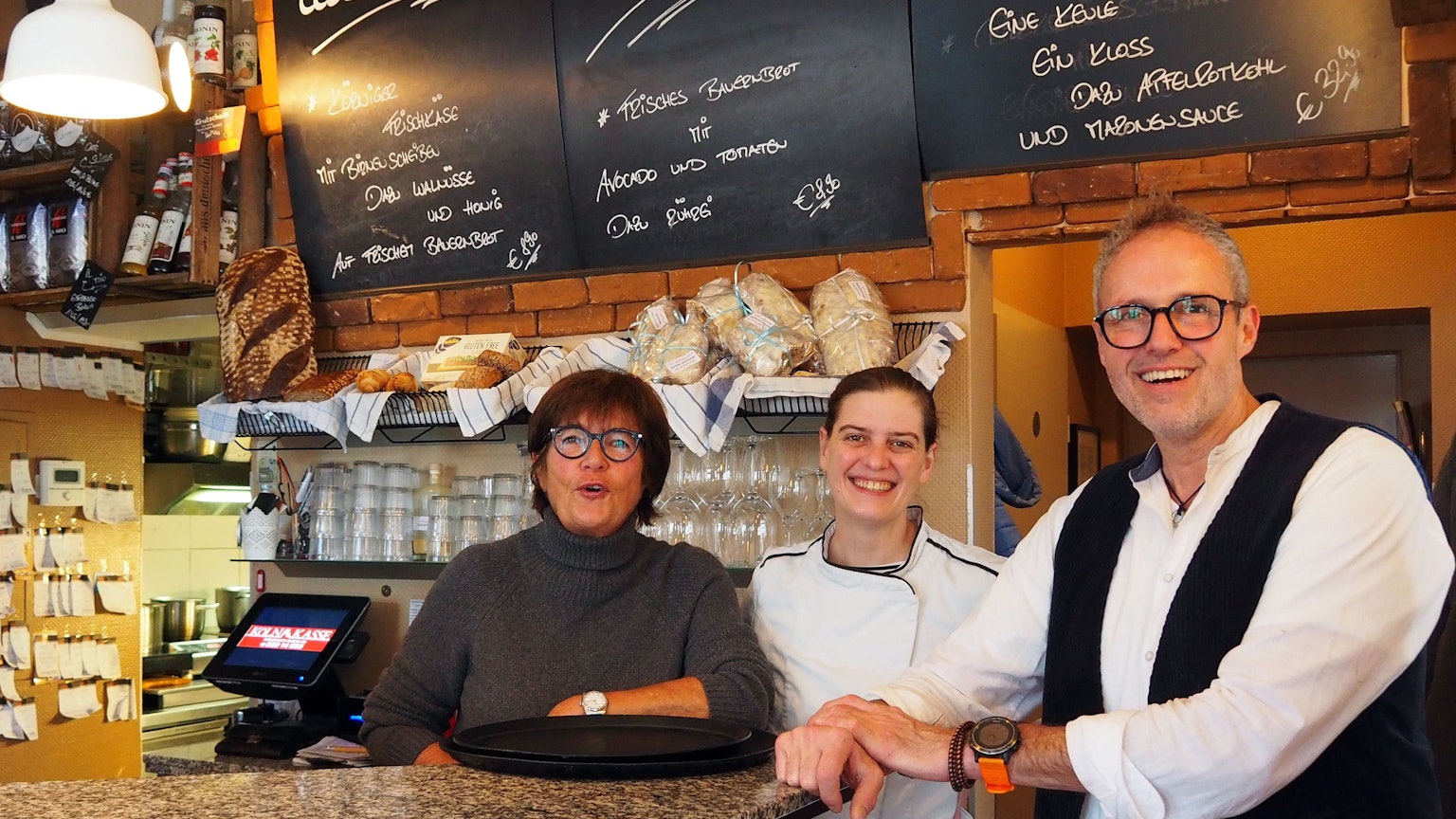 Brigitte Breiter (Köchin), Esther Raderberger und Olaf Schlien (Inhaber) im Café Haptilu im Kartäuserhof hinter der Theke.
