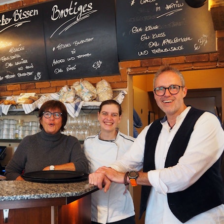Brigitte Breiter (Köchin), Esther Raderberger und Olaf Schlien (Inhaber) im Café Haptilu im Kartäuserhof hinter der Theke.