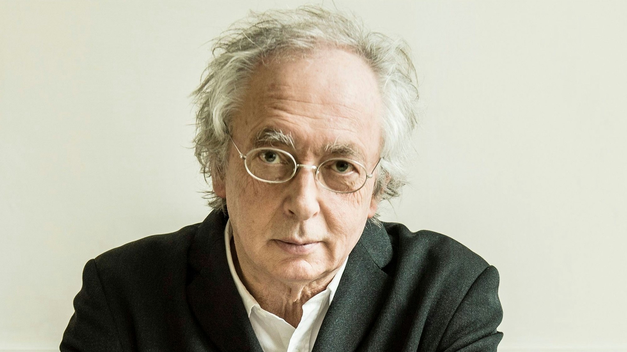 Der flämische Dirigent Philippe Herreweghe. Er trägt ein weißes Hemd und darüber einen schwarzen Mantel