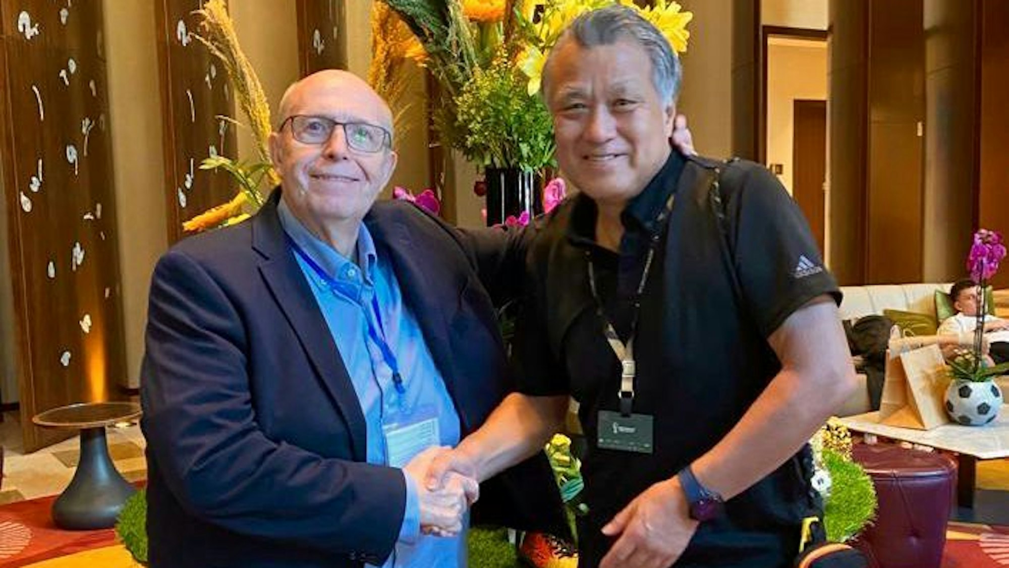 Reiner Calmund, der ein blaues Hemd und ein dunkelblaues Sakko trägt, traf in Doha seinen langjährigen Bekannten Kōzō Tashima, den Präsidenten des japanischen Fußballverbands.