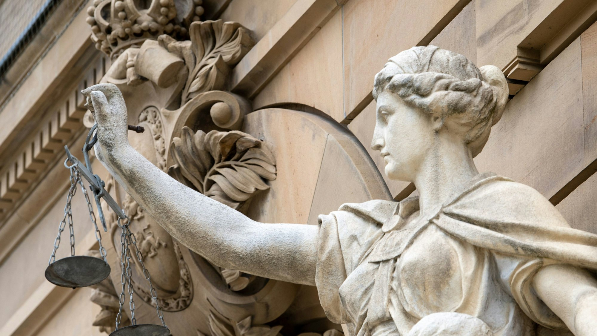 Eine Statue der Göttin Justitia hält eine Waagschale in der Hand.