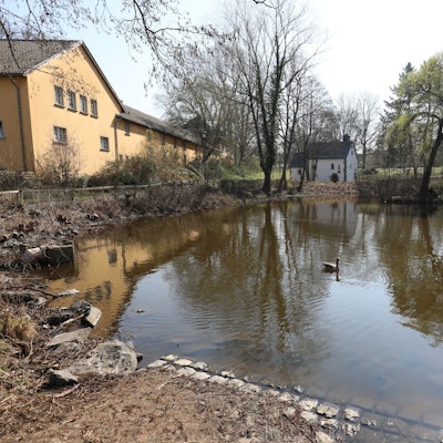 Ein Teich mit relativ niedrigem Wasserstand, im Hintergrund steht eine kleine Kapelle.