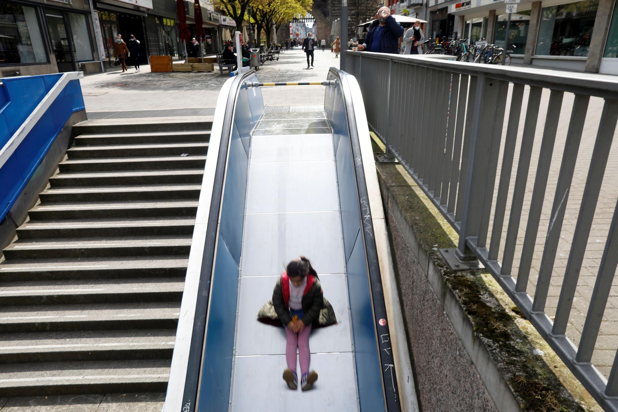 Das Bild zeigt ein Mädchen, das am Ebertplatz eine Rutsche auf einer kaputten Rolltreppe hinunter rutscht.