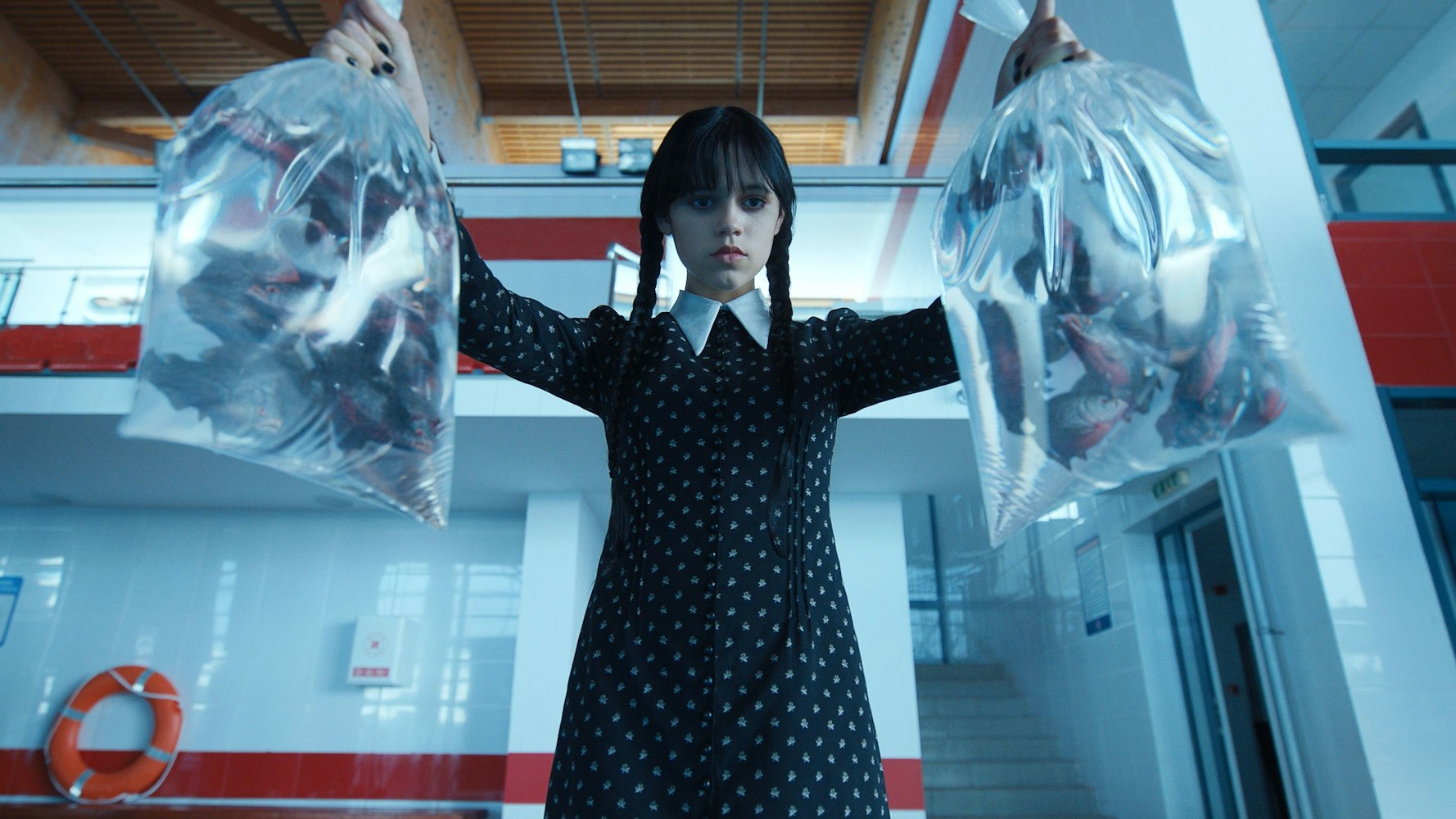 Jenna Ortega als Wednesday Addams mit zwei Tüten voller Piranhas