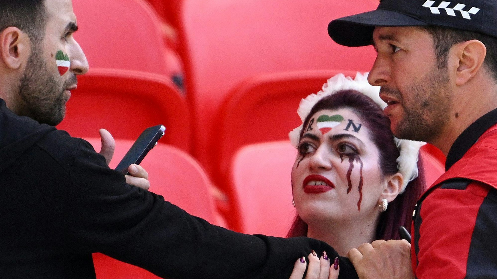 Eine katarische Sicherheitskraft diskutiert mit zwei Zuschauern, die sich mit der Protestbewegung im Iran solidarisert hatten.