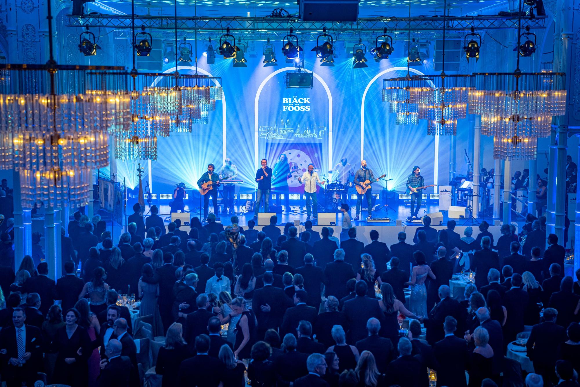 Auf einer blau ausgeleuchteten Bühne spielt die Kölner Band Bläck Fööss.