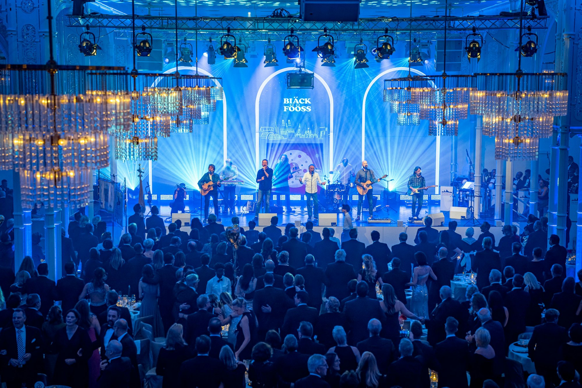 Auf einer blau ausgeleuchteten Bühne spielt die Kölner Band Bläck Fööss.