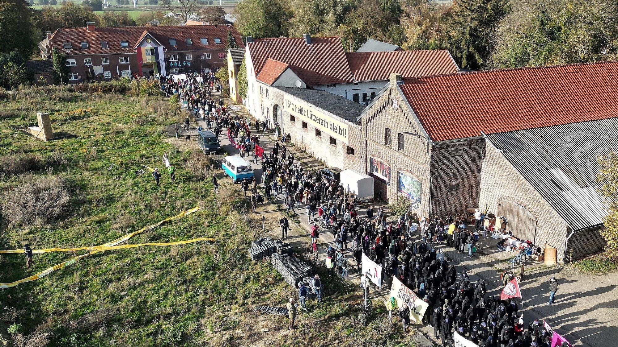 Bei einer Demonstration in Lützerath ziehen mehrere Hundert Teilnehmer mit Banner durch das Dorf.