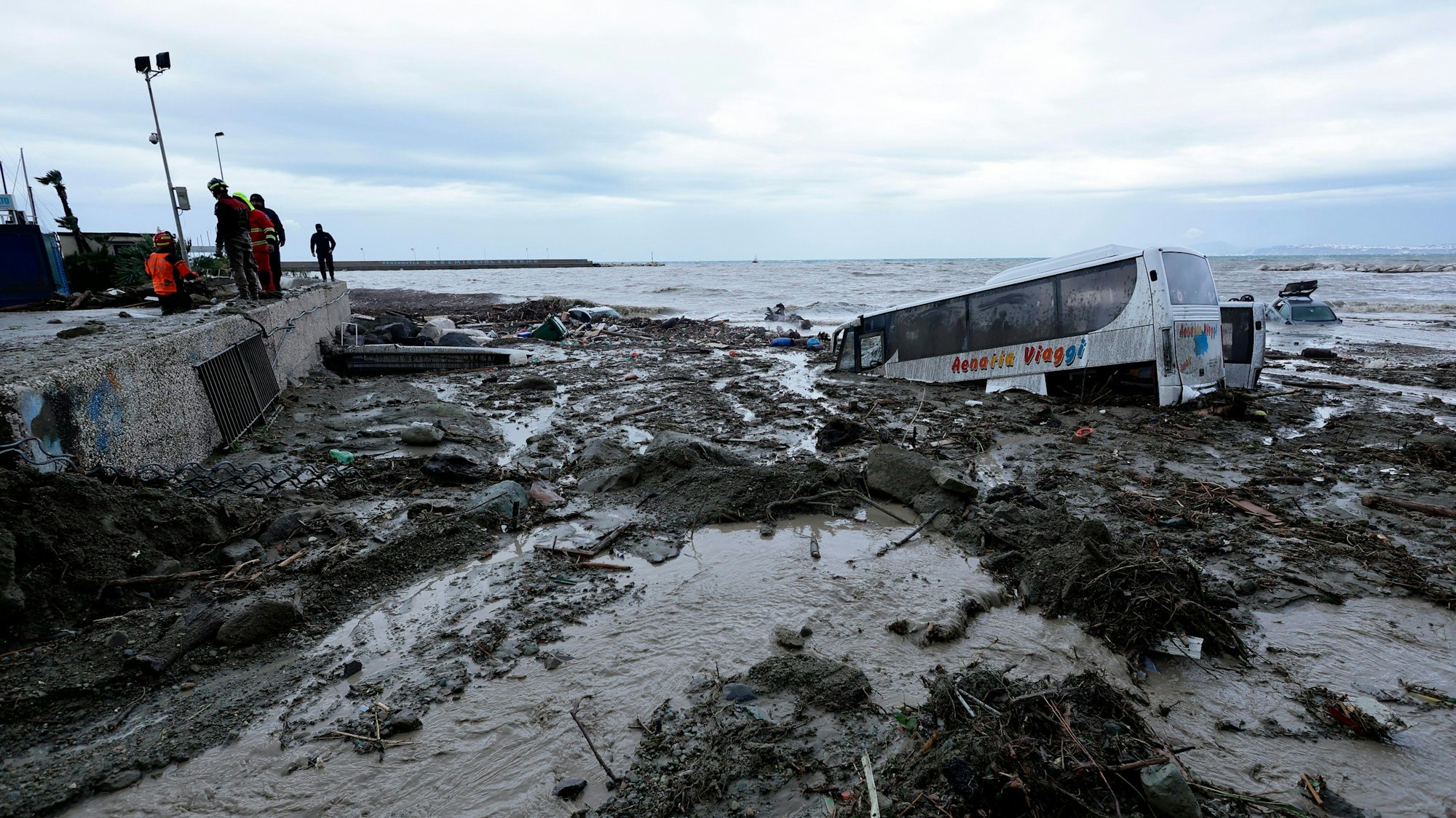 Rettungskräfte stehen in Casamicciola auf Ischia neben einem Bus, der durch schwere Regenfälle weggeschwemmt wurde.