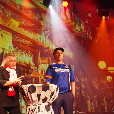 Tommy Engel und Ingolf Lück in Fußball-Trikot mit Regenbogen-Armbinde auf der Bühne des Weihnachtsengel.