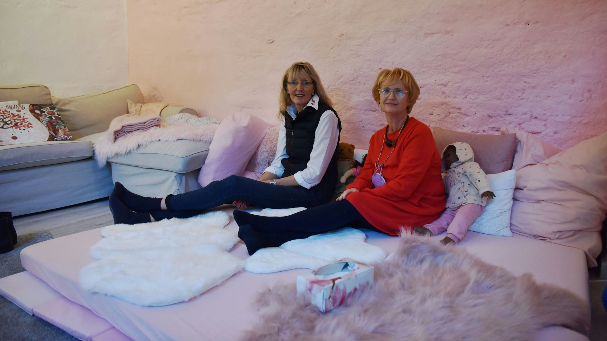 Heike Iven (DRK) und Miriam Nachtkamp sitzen im Beratungszimmer des Henrys Eltern-Kind-Kompetenzzentrum. Das Zimmer ist bewusst gemütlich und kuschelig gestaltet