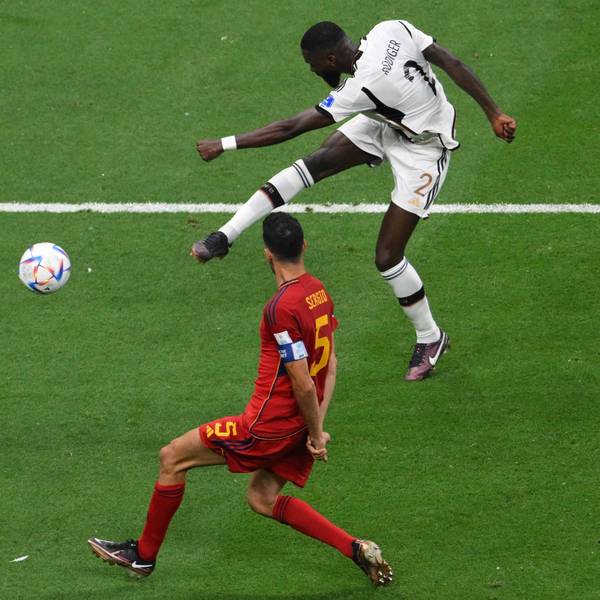 Antonio Rüdiger versucht im WM-Spiel gegen Spanien einen Fernschuss und macht dabei keine besonders elegante Figur. Spaniens Sergio Busquets versucht, den Schuss zu blocken.