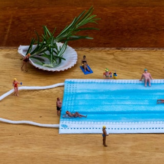 Symbolisch bewegen sich Püppchen um eine Corona-Schutzmaske wie in einem Bad.