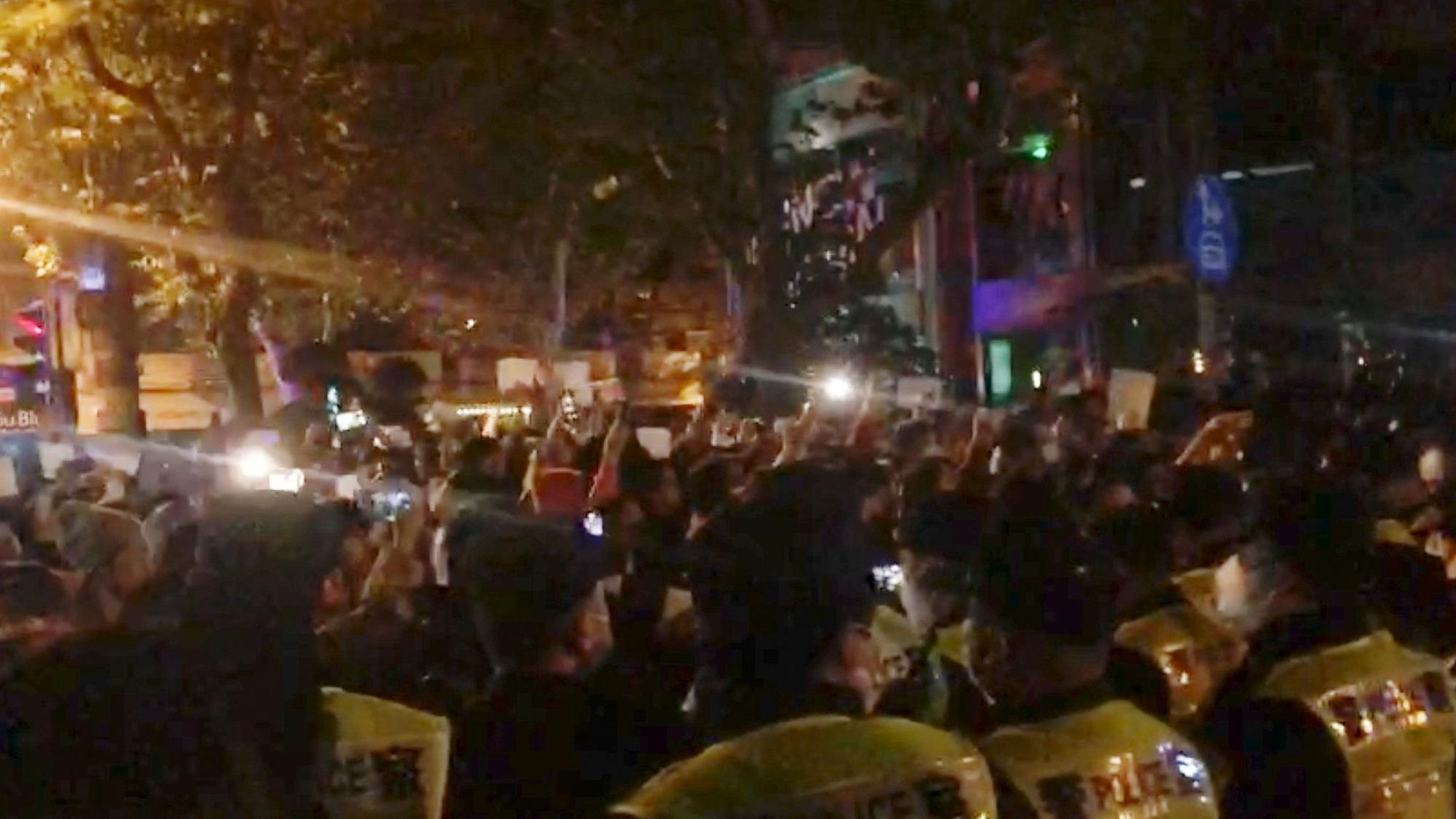 In diesem Bild aus einem Video, das The Associated Press erhalten hat, beobachtet die Polizei (im Vordergrund) die Demonstranten in Shanghai.