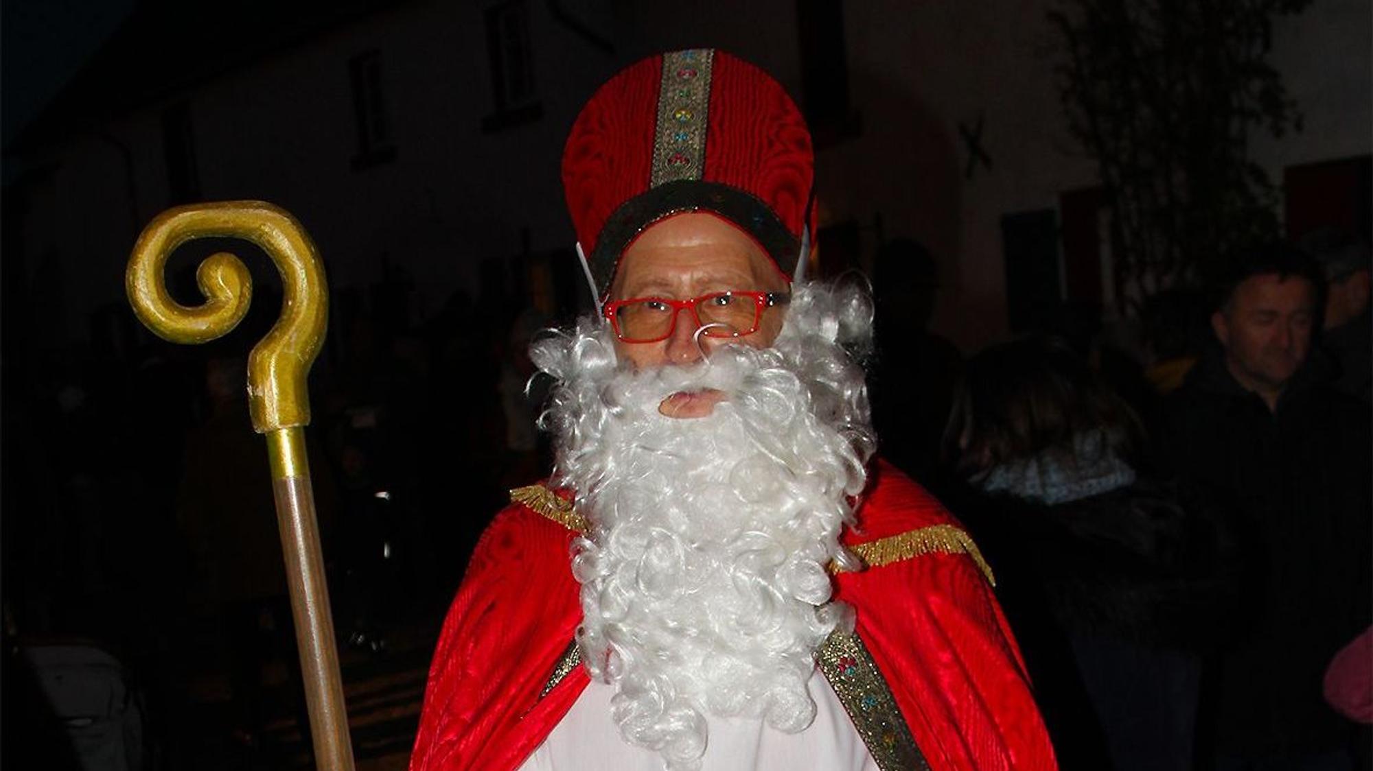 Heinz-Bert Weimbs, Vorsitzender des Ortskartells, ist als Nikolaus unterwegs. In seiner Hand hält er einen Korb mit Süßigkeiten für die Kinder.