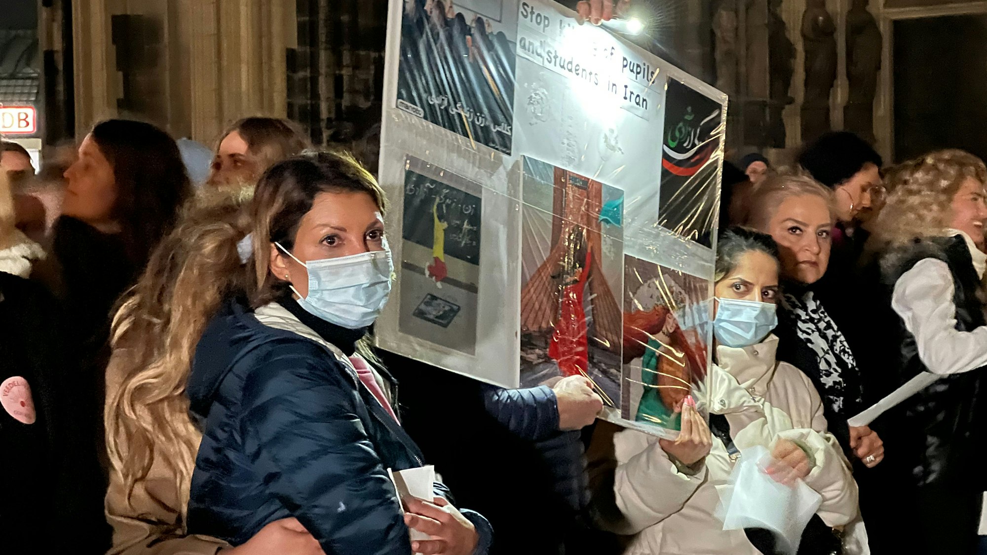 Hunderte Kölner singen „Another Love“ auf der Domplatte. Demonstrantinnen, einige mit Schutzmaske, halten Plakate hoch.
