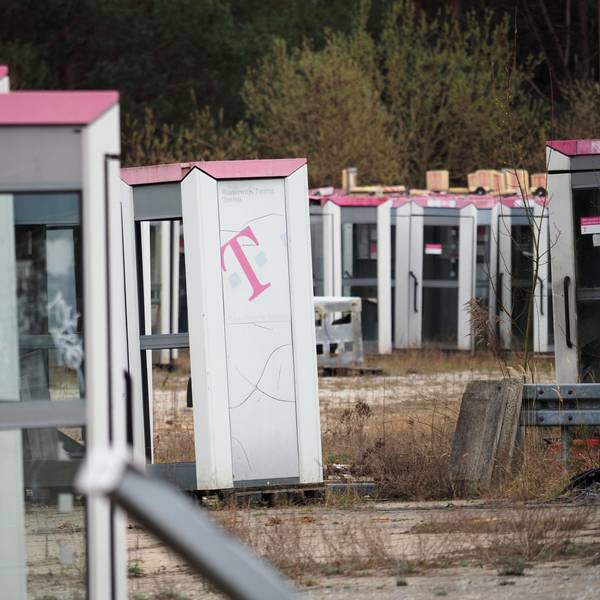 Ausrangierte Telefonzellen stehen auf einem abgezäunten Gelände in Brandenburg.