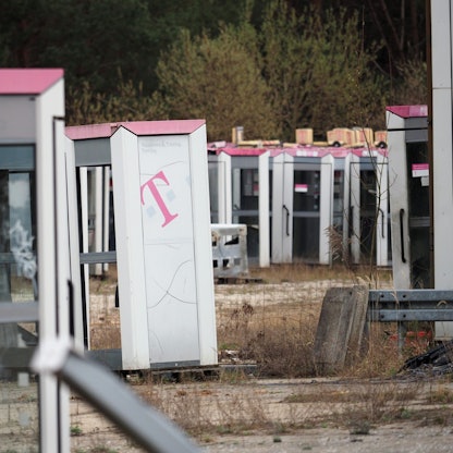Ausrangierte Telefonzellen stehen auf einem abgezäunten Gelände in Brandenburg.