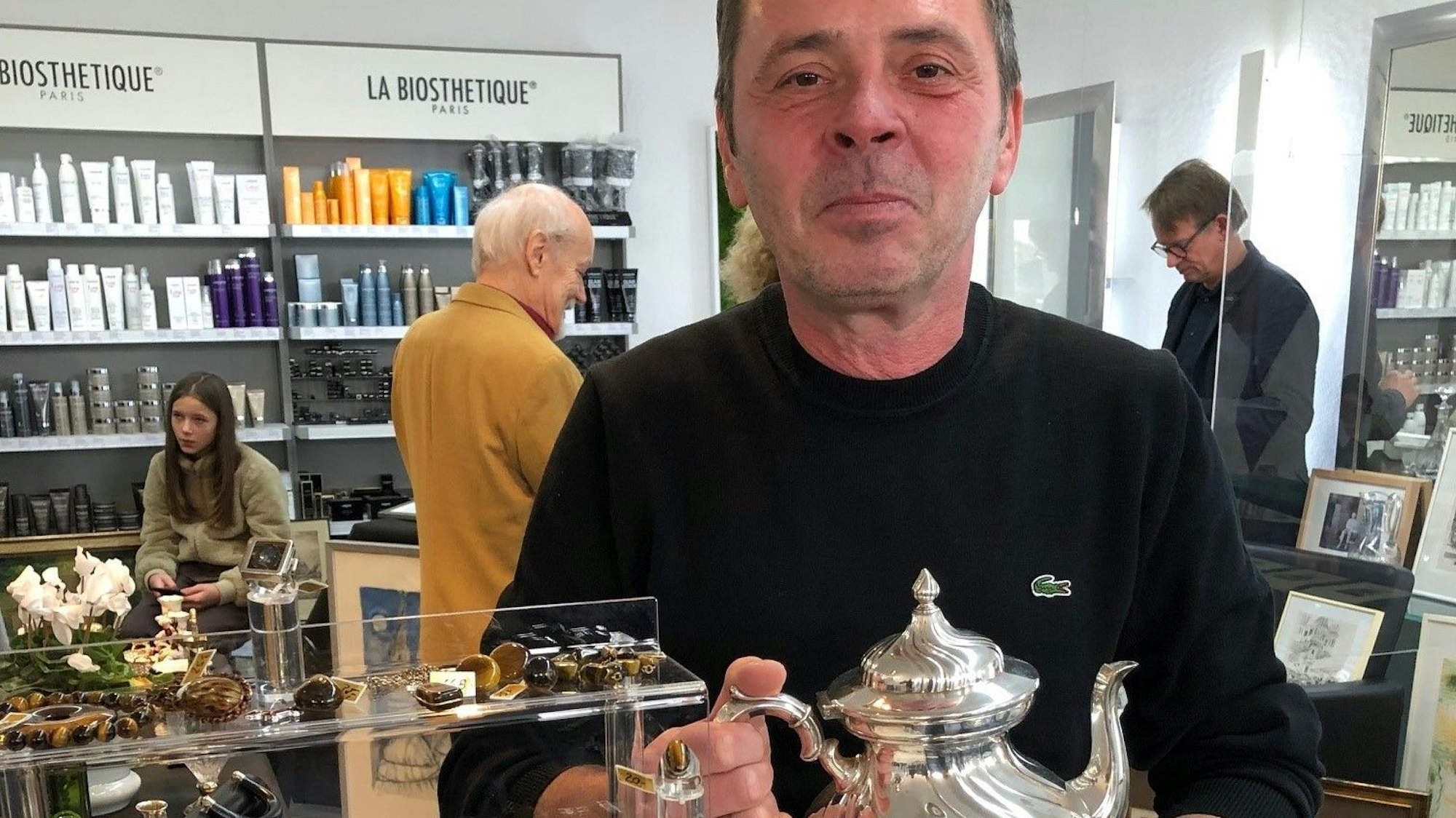 Friseurmeister Ralph Schwalbach steht in seinem Salon an der Luxemburger Straße und hält eine Kanne aus Silber in der Hand.