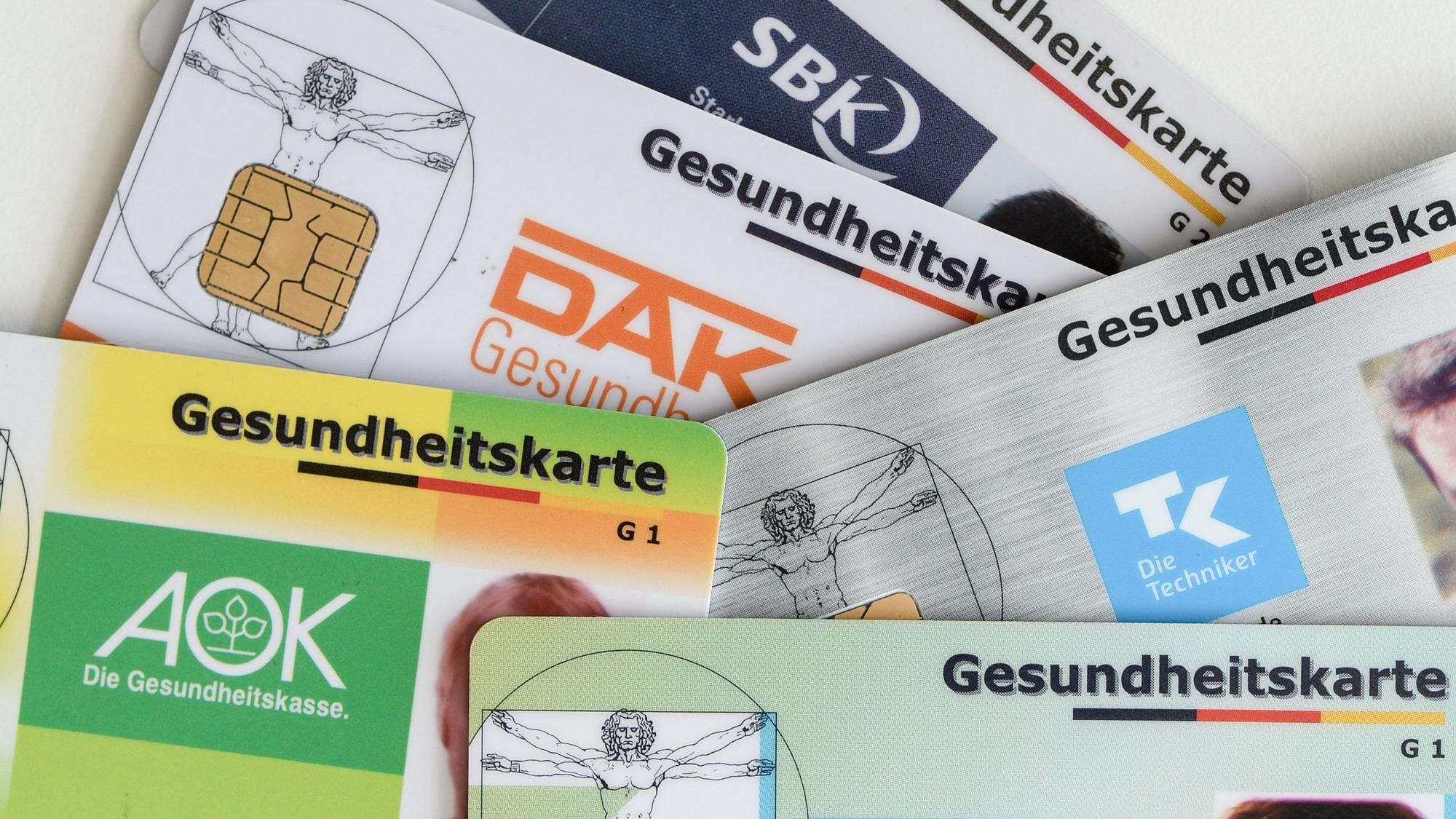 Gesundheitskarten verschiedener Krankenkassen liegen auf einem Tisch.