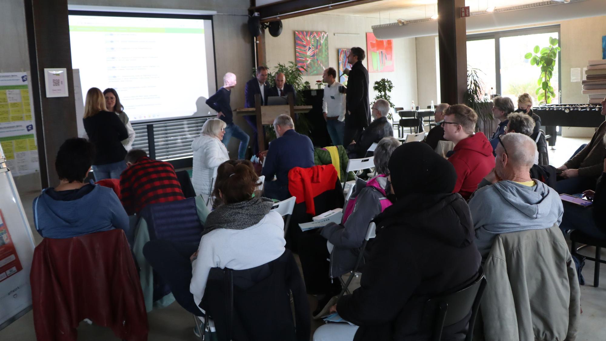 Die Bürgerinnen und Bürger schauen im Workshop auf eine Leinwand.